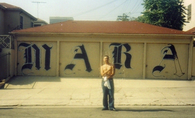 Stranger, pandillero de la clica Adams Locos, frente a un mural de la MS-13 situado en los alrededores de la calle Norton de Los Ángeles. La Adams se fundó a principios de los años 90. Fue una de las últimas clicas de la Mara Salvatrucha surgidas en Los Á